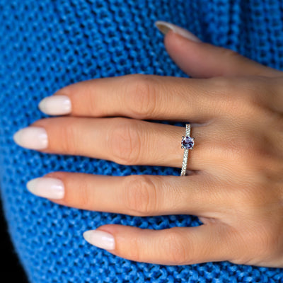 Hand wearing a white gold alexandrite  ring with a blue background
