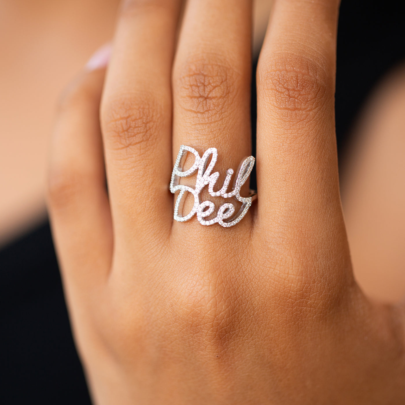 closeup of a women wearing a double name ring in 14K white gold set with diamonds