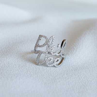 closeup of a custom double name ring in 14K white gold set with diamonds