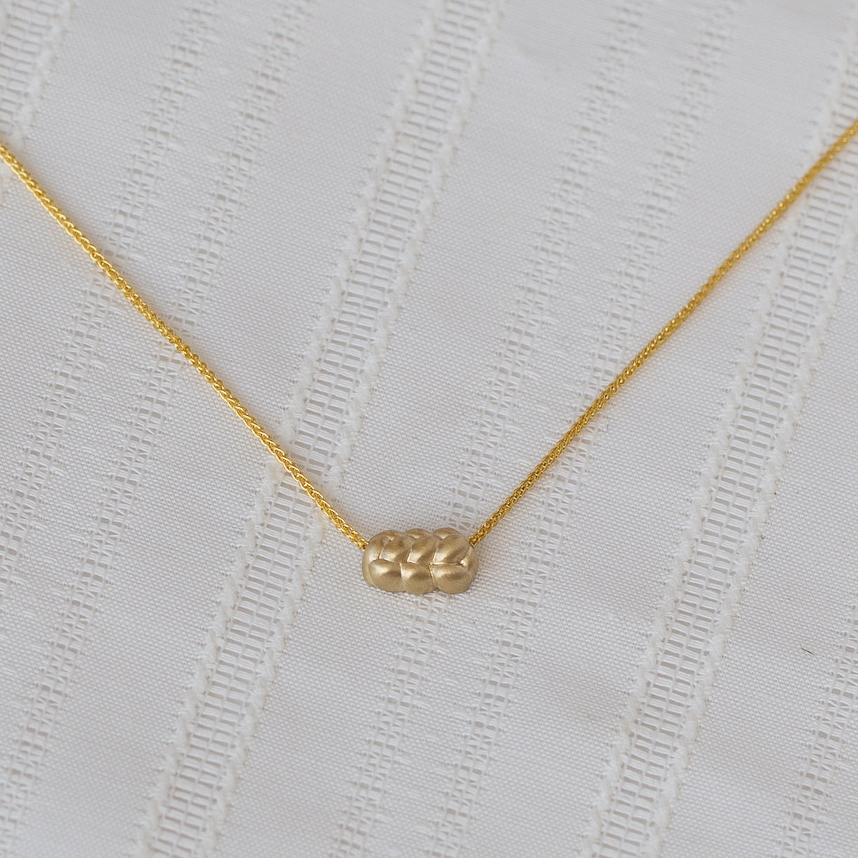 closeup of a 14K yellow Gold knot Necklace, with a challah pendant and dainty chain