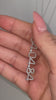 Video of a woman's hand holding a custom diamond numbers necklace in 14k white gold