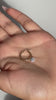 Video of a hand holding and showing a gold diamond hoop earring with a dangling charm.