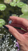 hand holding an aquamarine engagement ring in white gold