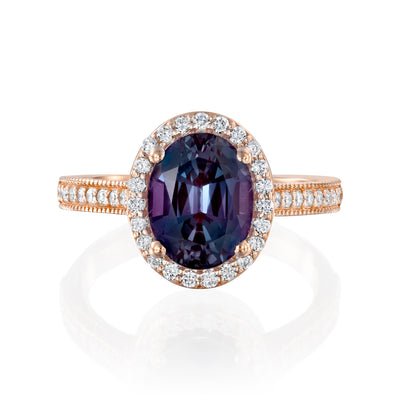 Rose gold ring with a purple gemstone and diamond halo on a white background
