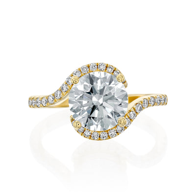 Gold ring with a 2ct moissanite and a smaller diamond halo on the band against a white background